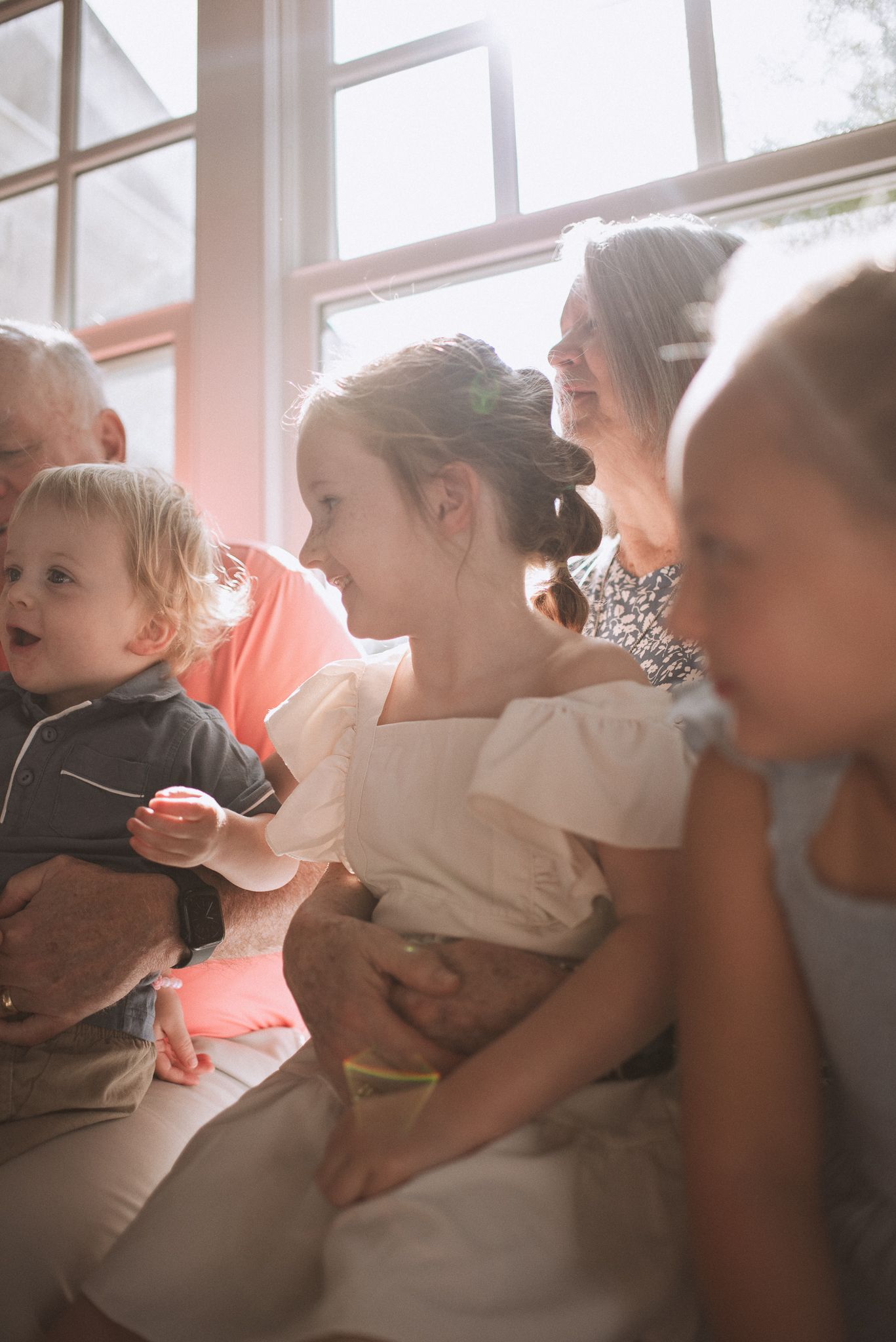 A series of soft, dreamy images showing tender moments between parent and child by a sunlit window.