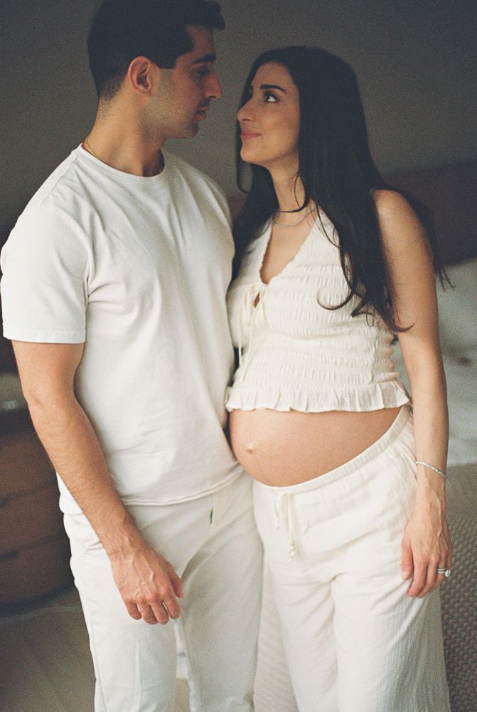 A romantic maternity photo series showing a couple in white clothing embracing in five intimate poses.