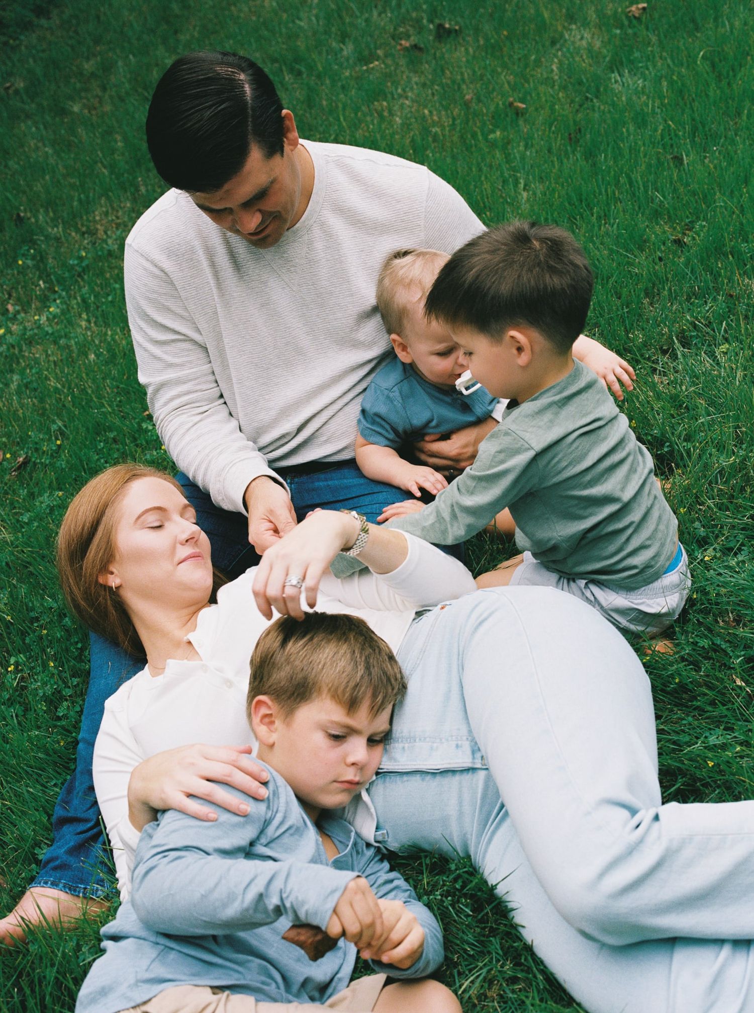A group relaxes together on green grass during a sunny afternoon outdoors.