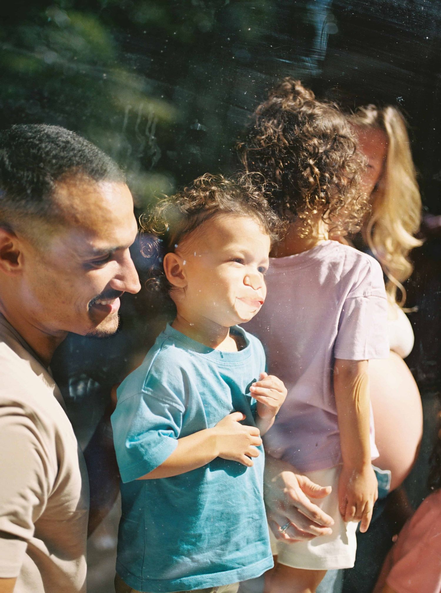 Group of children sit together outdoors on a sunny day.