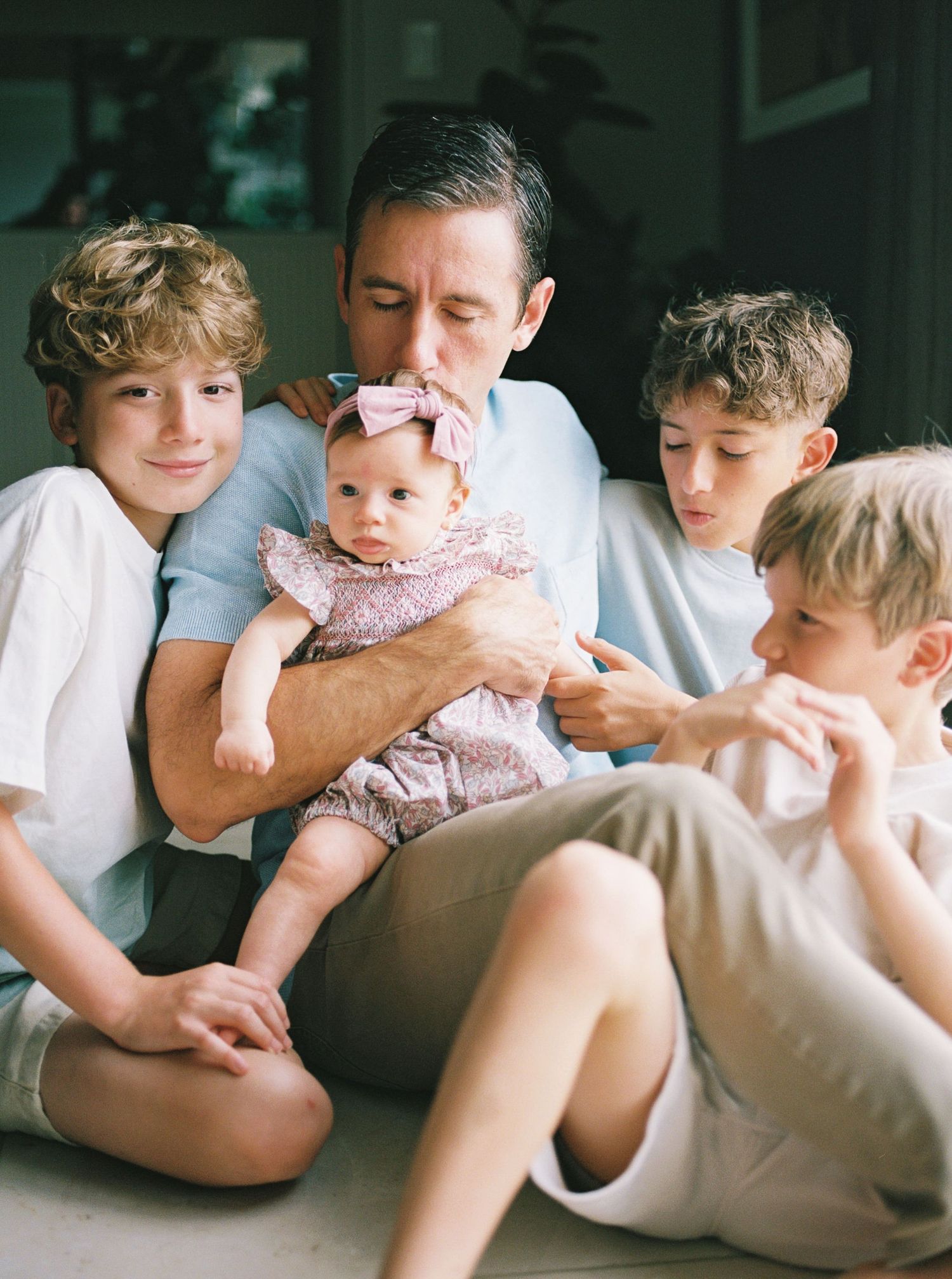 A series of candid family moments showing tender interactions with a baby in pink clothing.