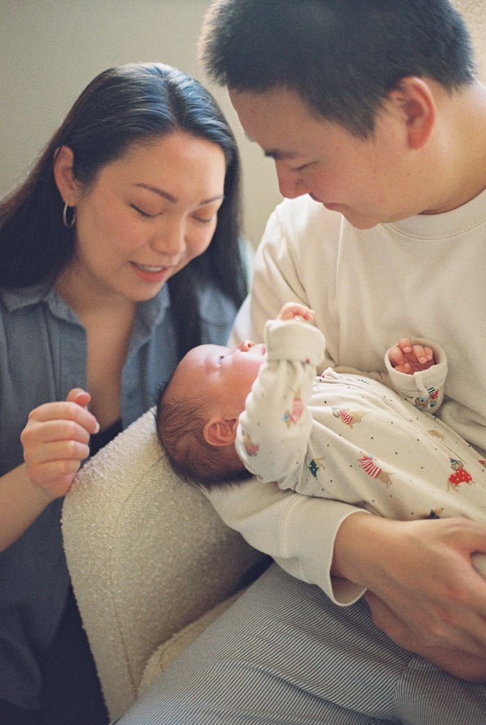 Parents lovingly gaze at their newborn baby wrapped in a white blanket.