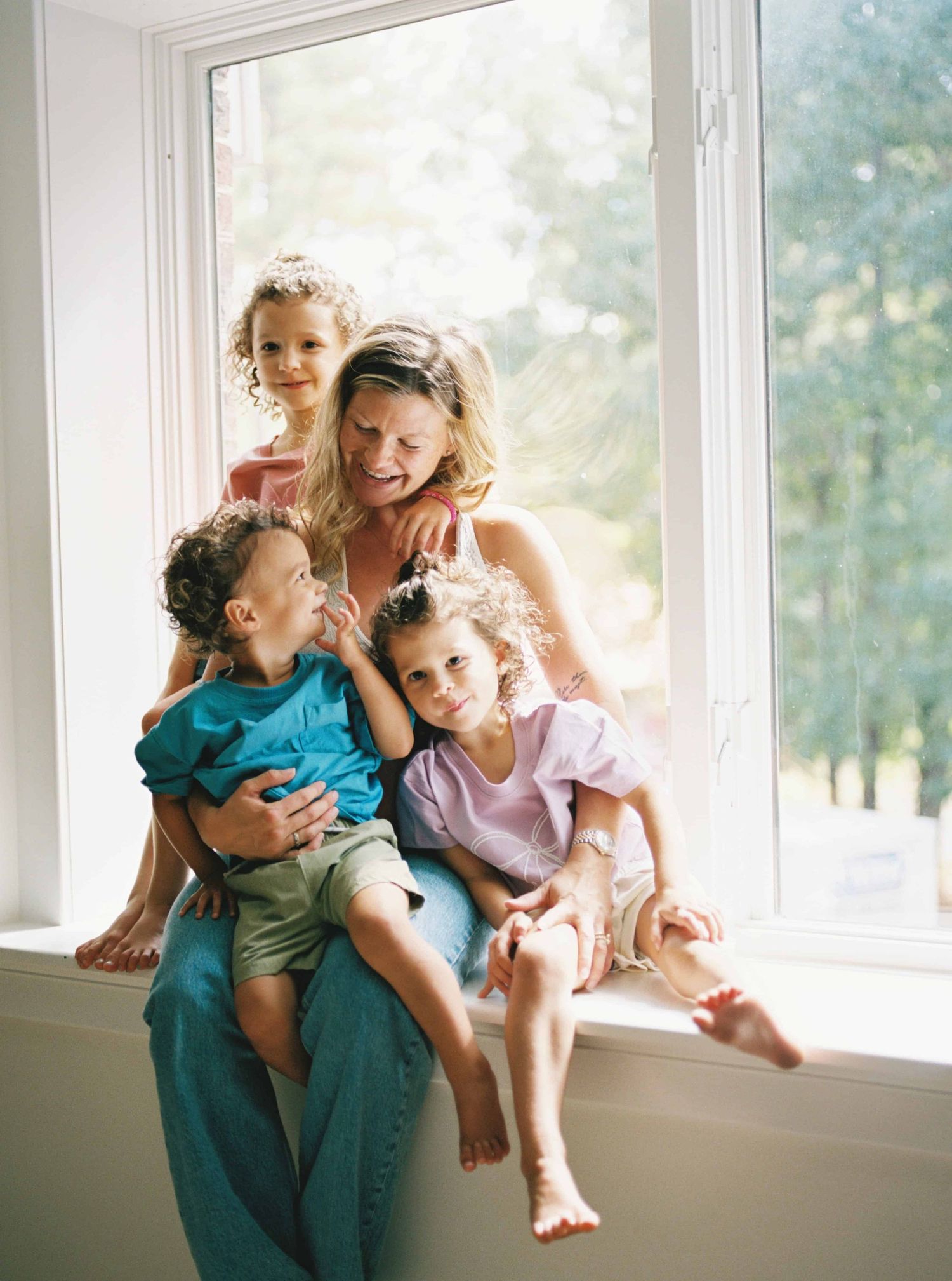 Family enjoying playful moment together by sunny window in bright interior setting.