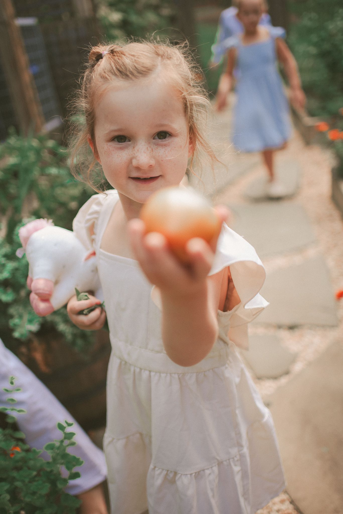 A series of photos showing a child in a white dress playing with bubbles in a garden setting.