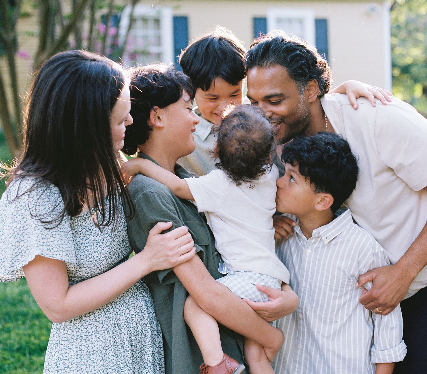 A loving family shares an intimate moment together outdoors, hugging and smiling in close embrace.