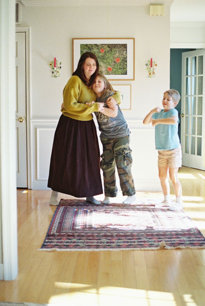 A series of four connected photos showing playful movement and interaction on a patterned rug in a bright interior space.