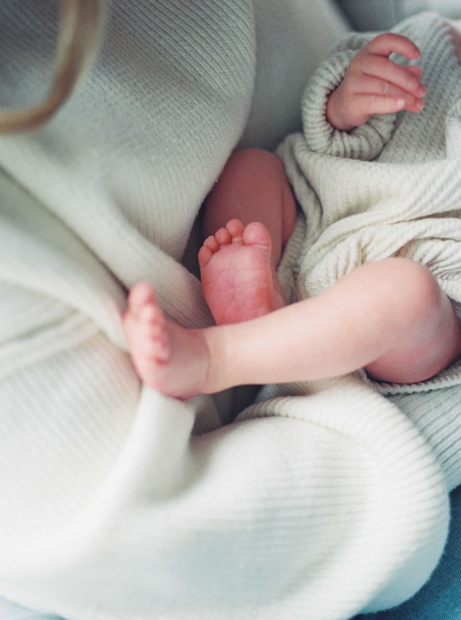 A collage of newborn baby hands and feet wrapped in soft white blankets showing delicate details and tiny features.