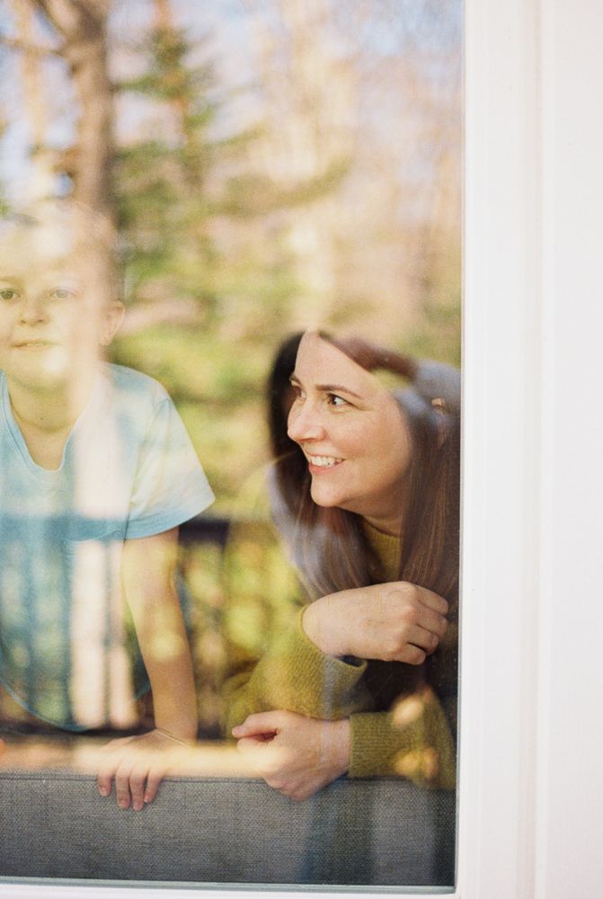 Three sequential photos through a window show a person smiling and laughing in warm natural light.