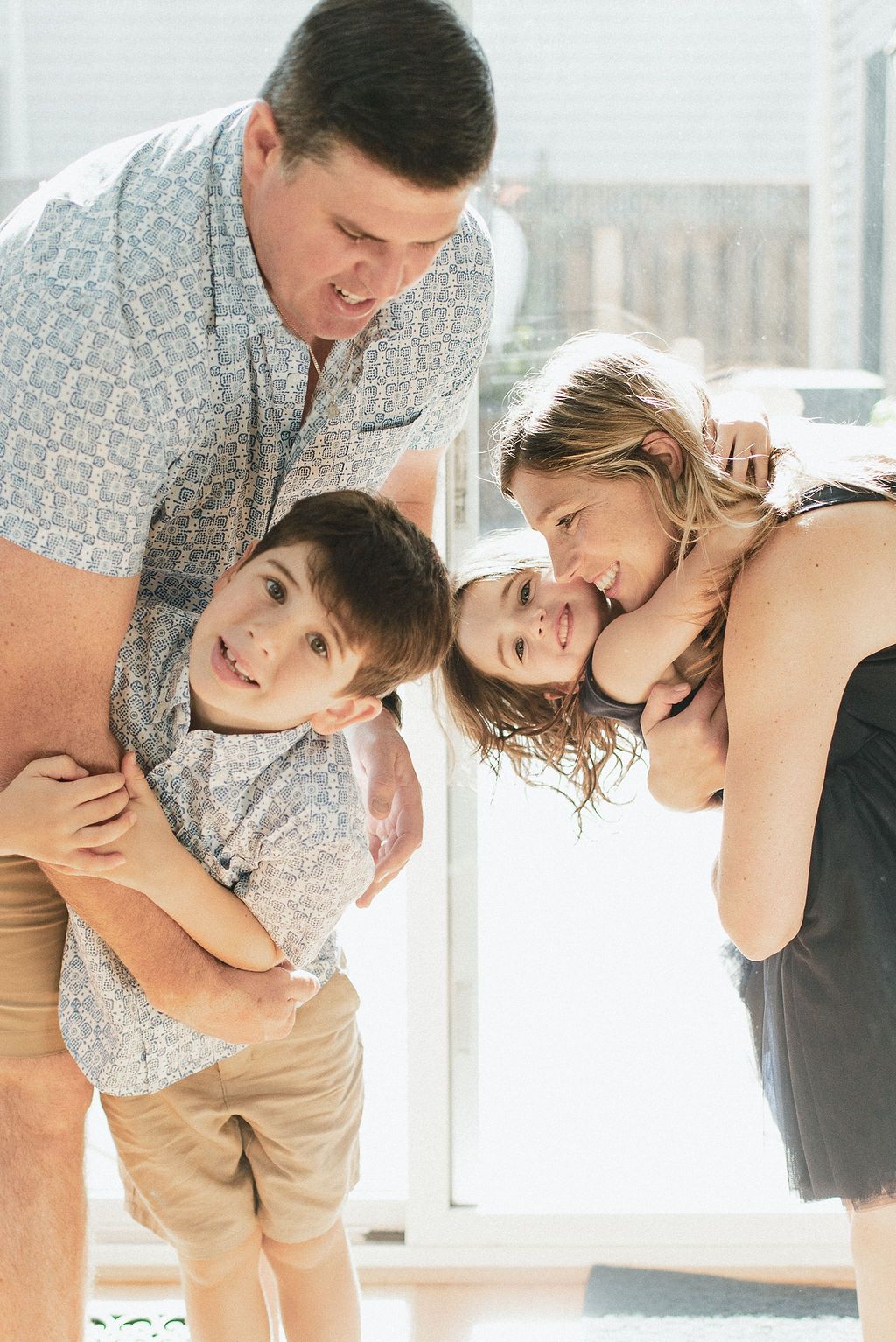 A couple shares playful and intimate moments in a bright sunlit room while wearing casual attire.
