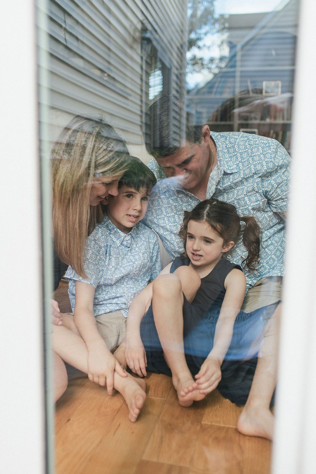 Family members peek through window frame while playing together at home.