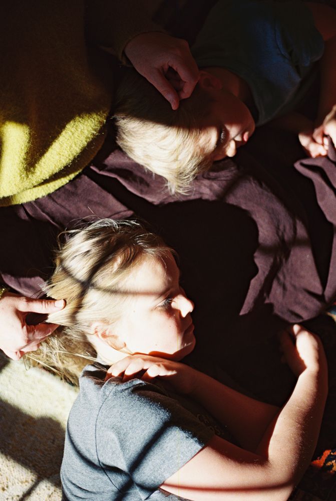 A person rests peacefully in a dimly lit room with sunlight streaming through a window.