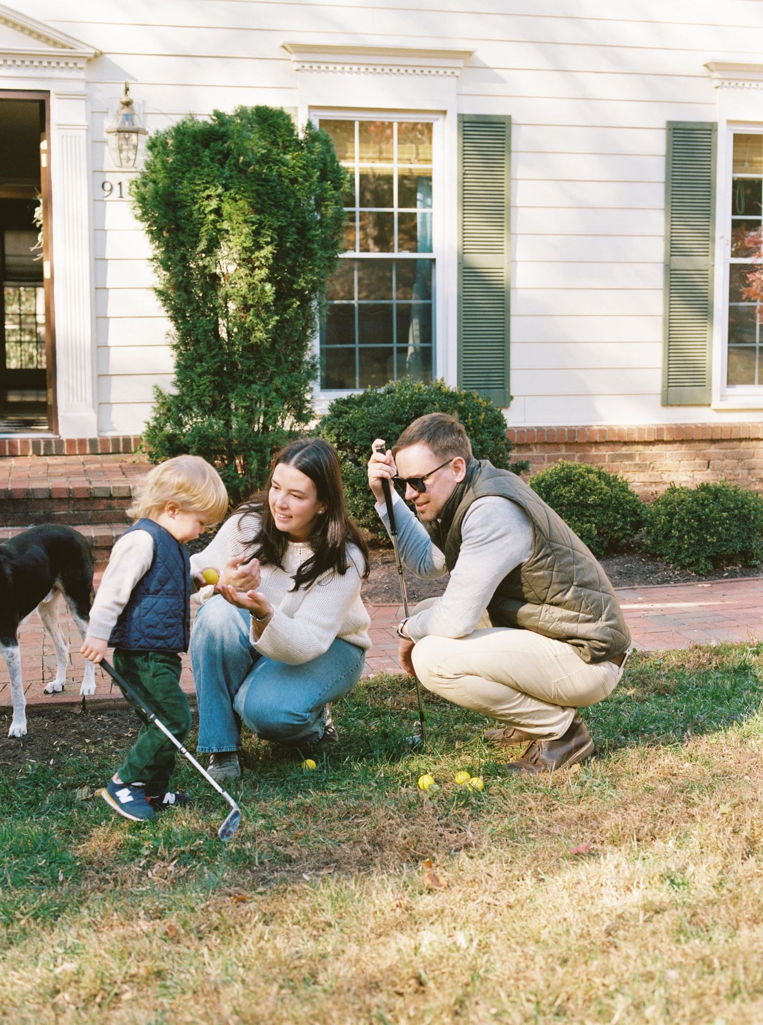 A sequence of four photos showing people crouched down in a line along a grassy yard outside a white house.