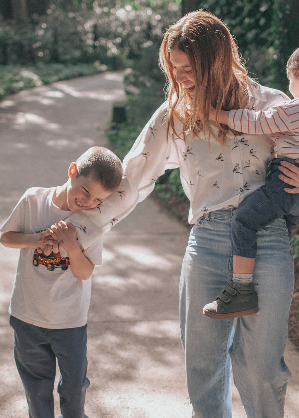 A person in jeans and white top dances with joy in a garden setting creating a sequence of flowing movements.