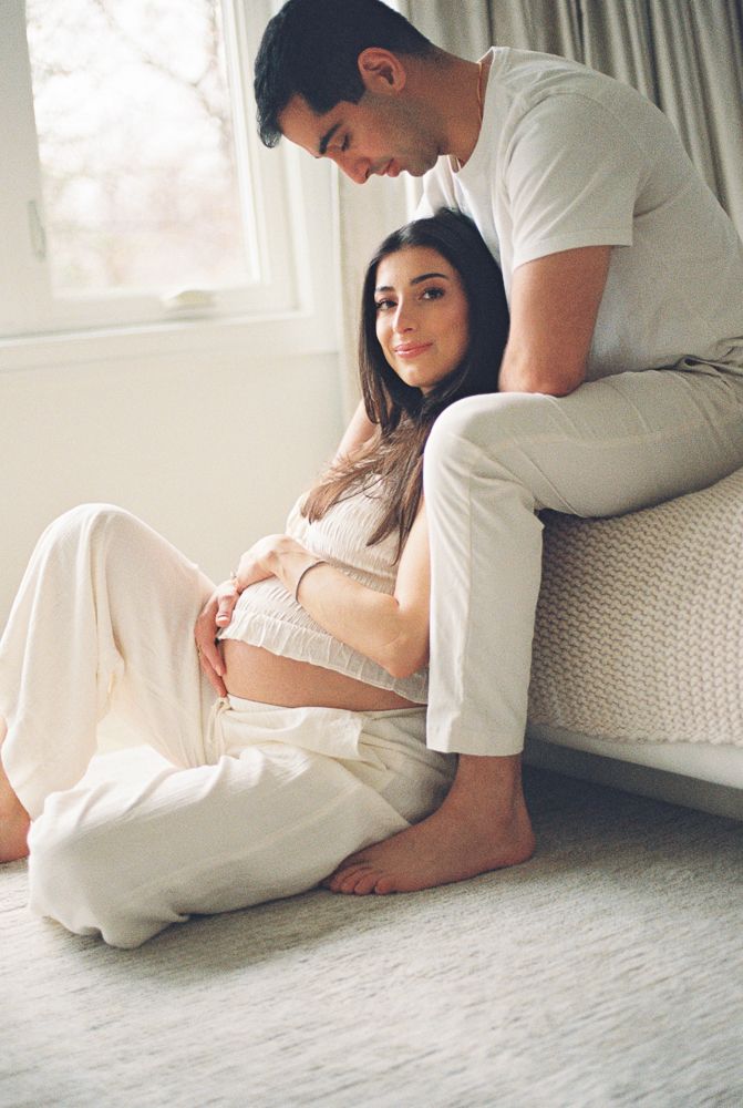 A couple shares an intimate moment on a light colored carpet in a series of connected maternity photographs.