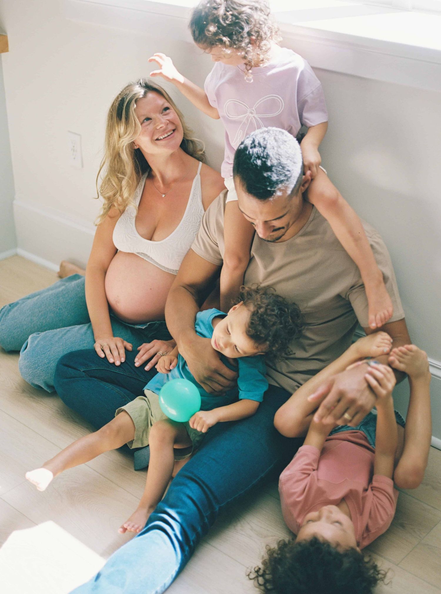 Family members sitting together on floor sharing intimate moments and laughter.