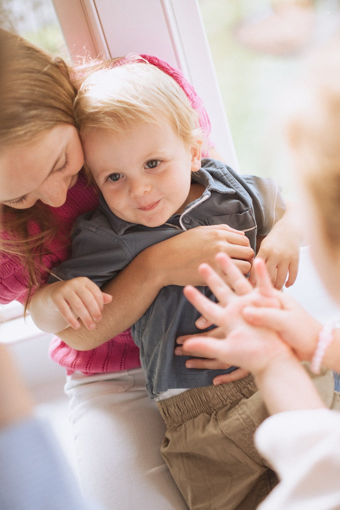 A tender moment between parent and toddler in gray clothing sharing an embrace and smile.