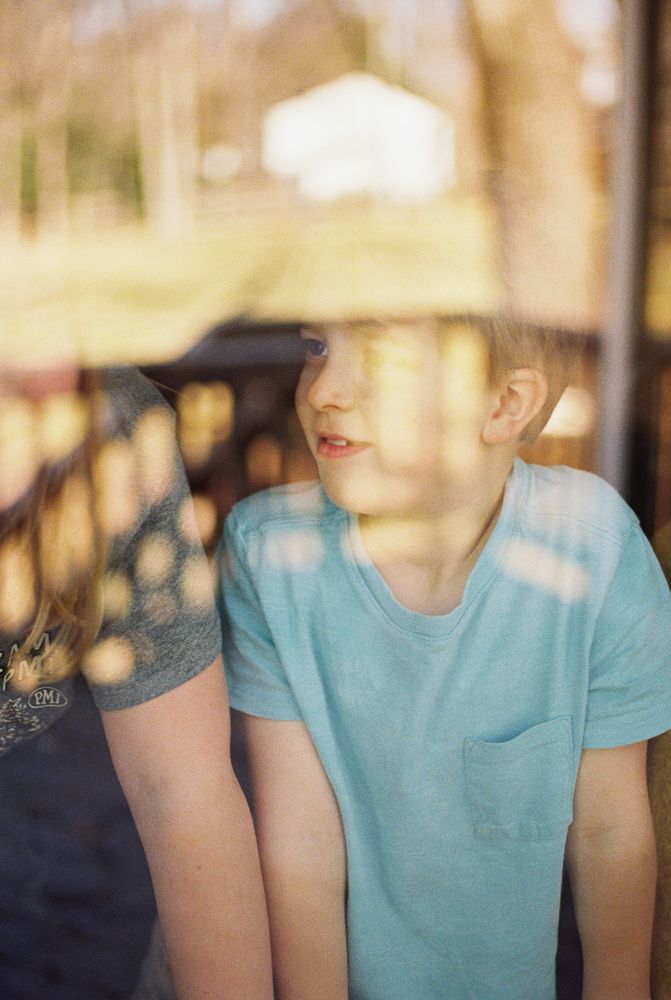 A person wearing a light turquoise t-shirt shown from shoulders down in a soft focus outdoor setting.