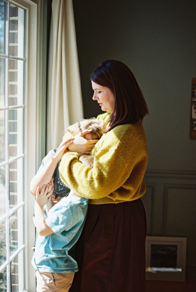 A series of connected images showing someone in a yellow sweater holding and comforting a small child by a window.