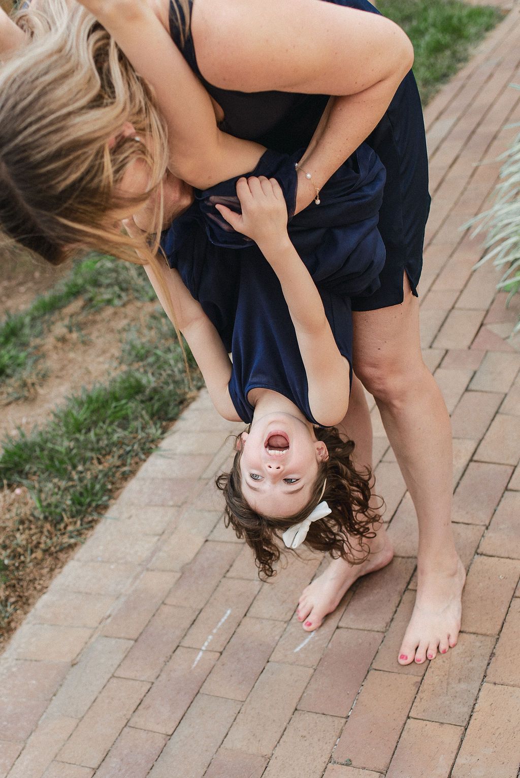 A sequence of photos showing someone in a navy dress bending down to touch their toes on a brick pathway.