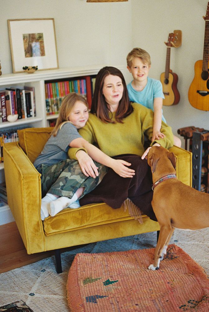 A sequence of five photos showing a dog jumping onto a yellow velvet couch in a living room with guitars on the wall.