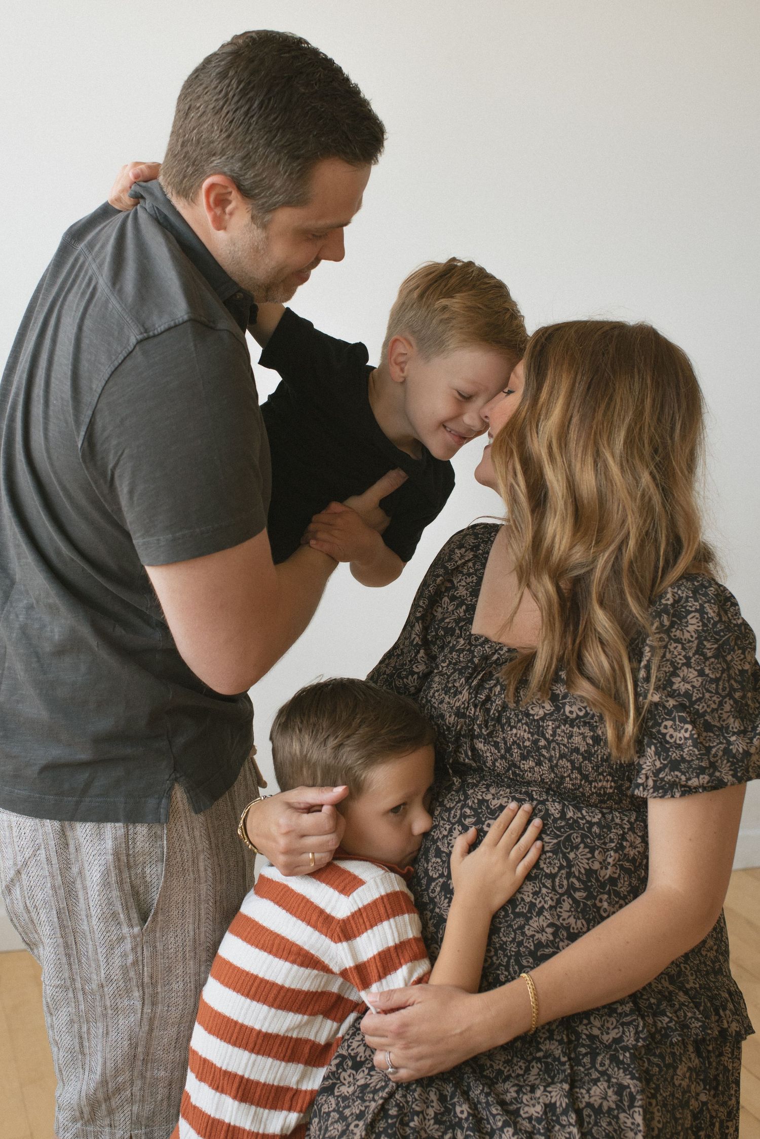 A family of three share an intimate moment embracing in a series of progressive candid photos against a light background.