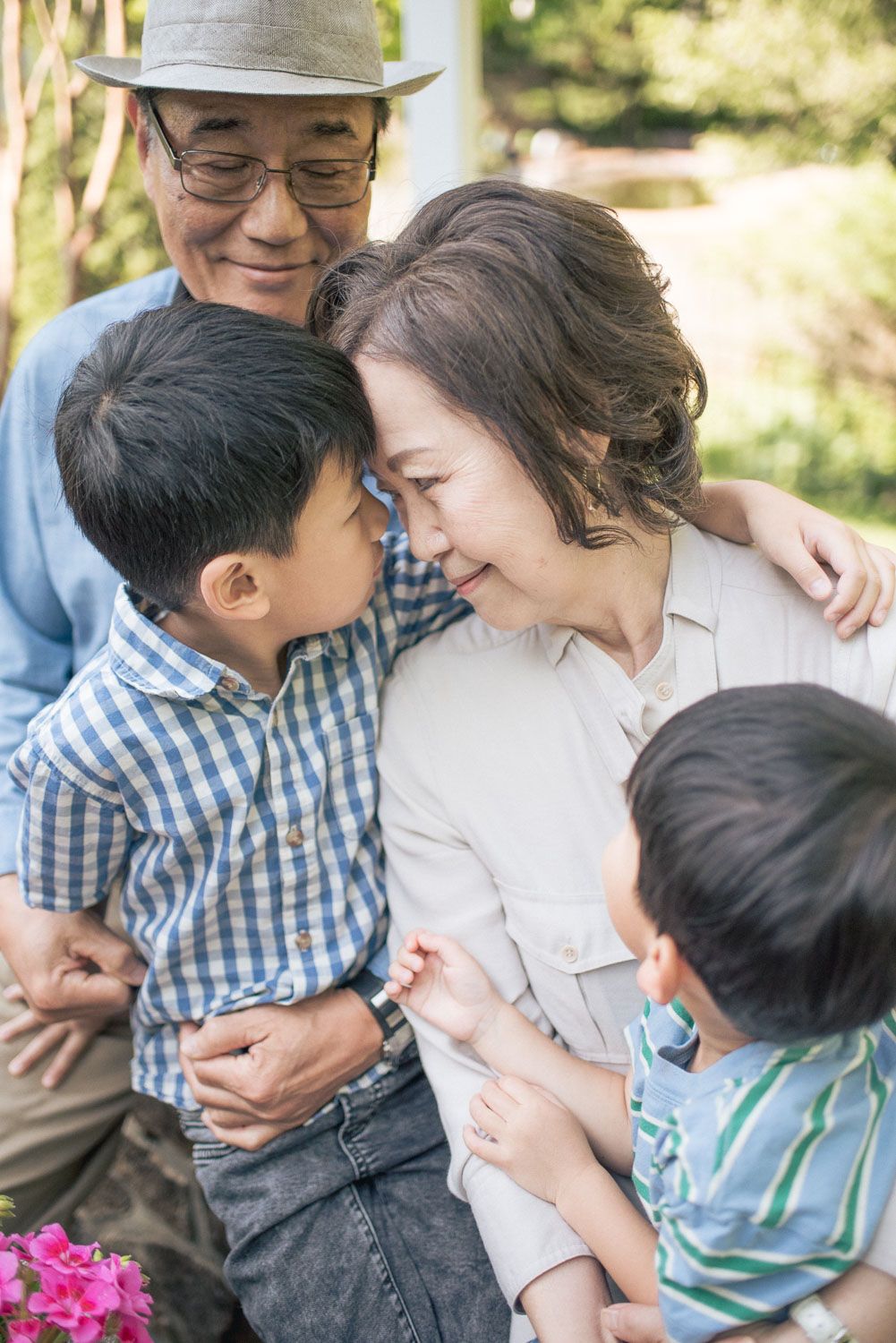 Grandparents sharing a tender moment with two young grandchildren outdoors in a garden setting.