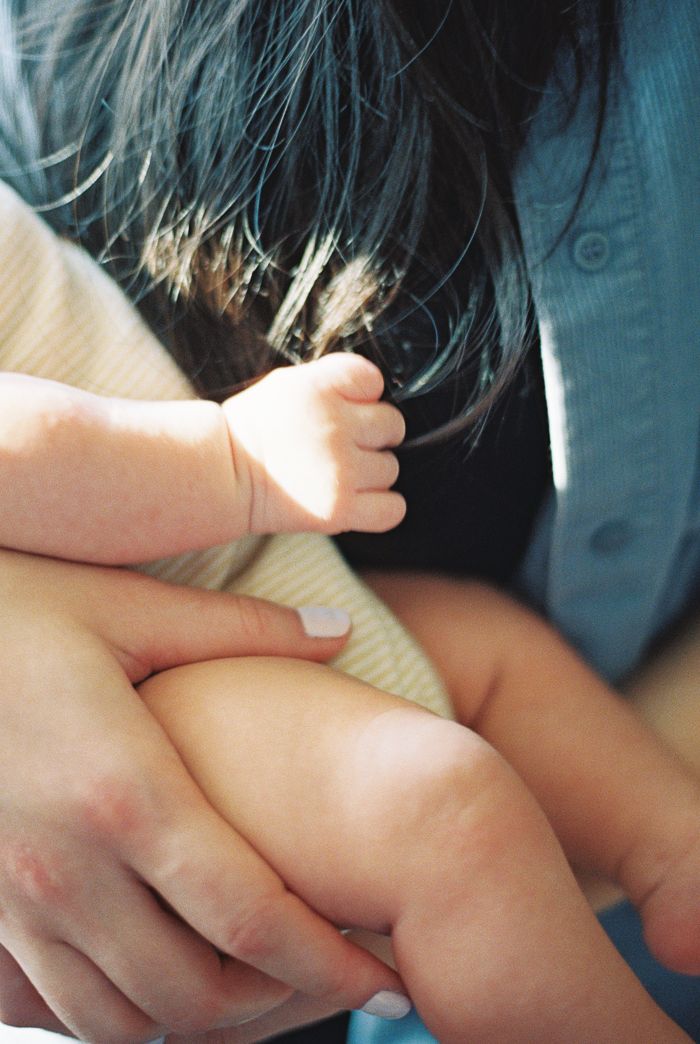 A newborn baby's tiny hand grasping an adult's fingers, symbolizing the bond between parent and child.