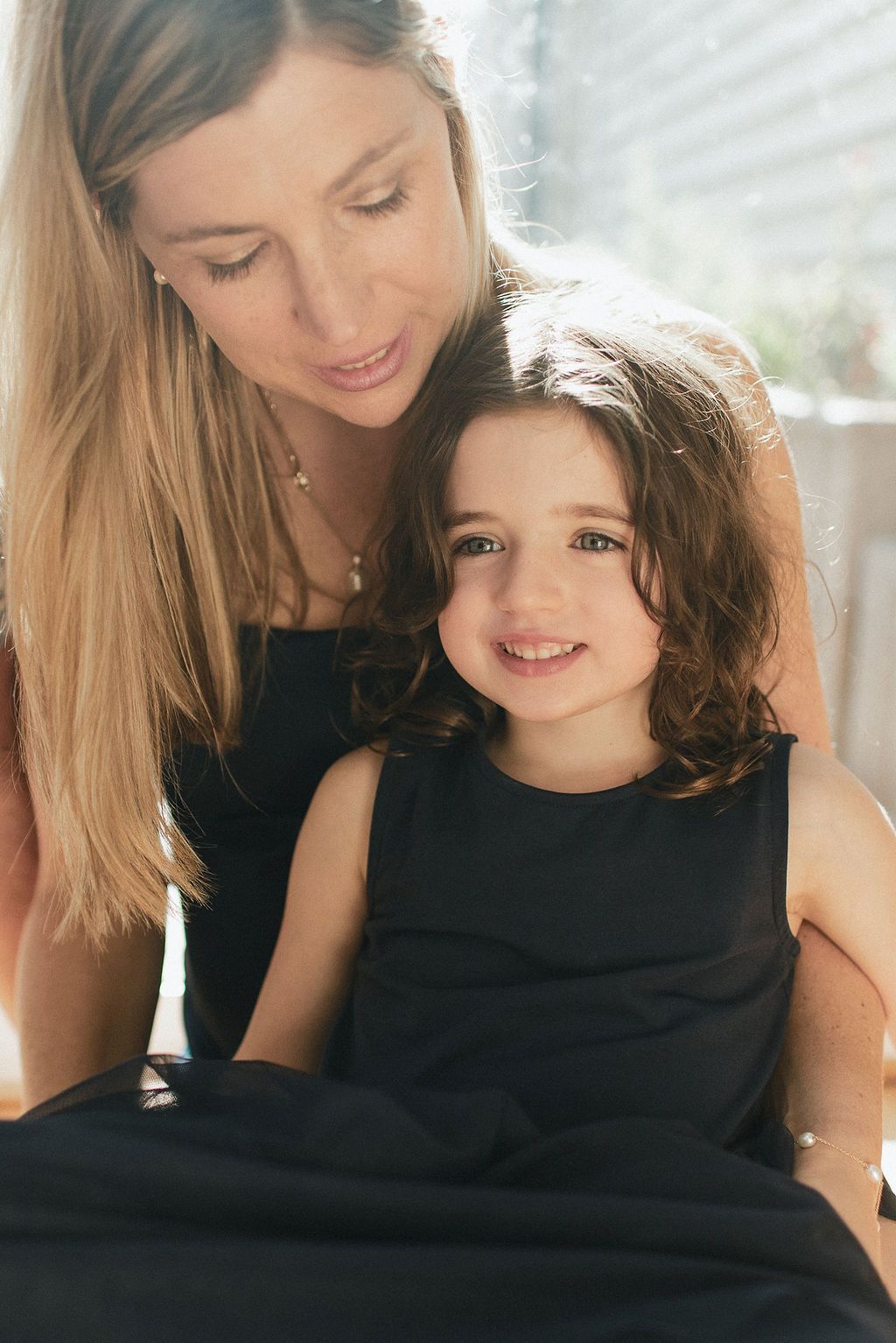 A tender moment between parent and child as they share laughter and cuddles while wearing matching black outfits.