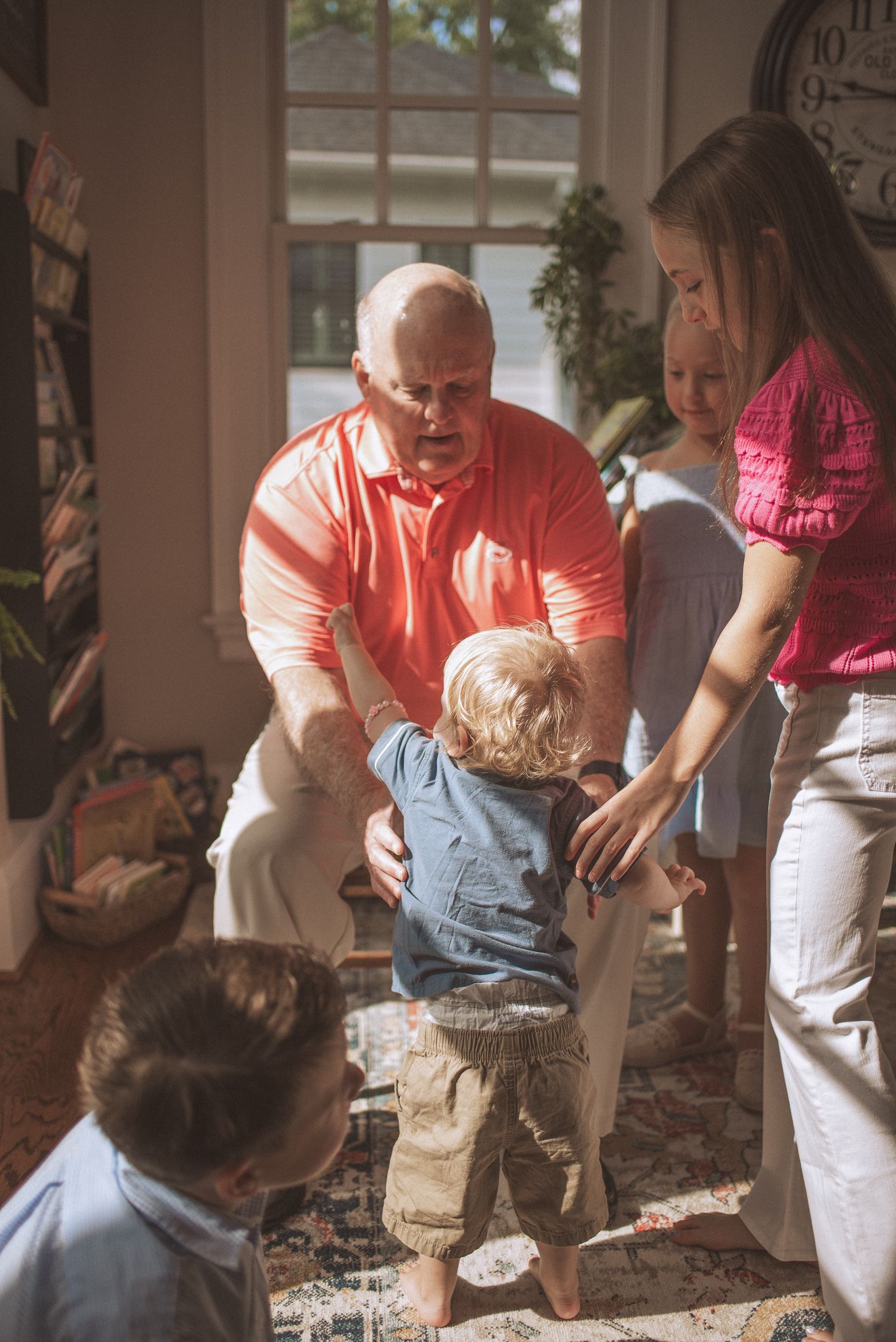 A sequence showing a person in a pink shirt interacting with a small child on a porch in a tender moment.