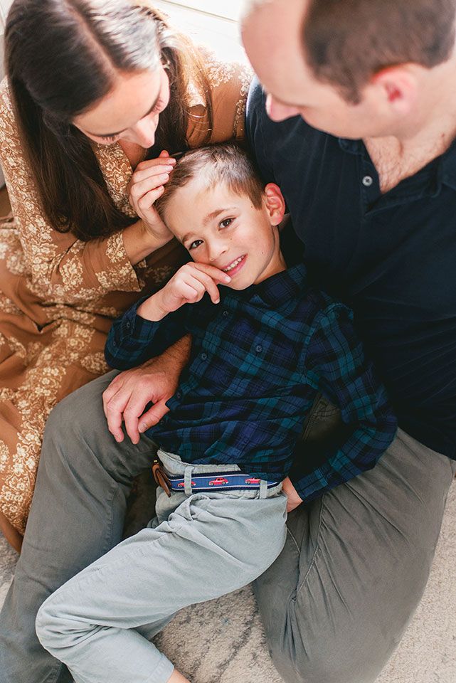A tender family scene with parents and child sharing playful moments on the floor together.