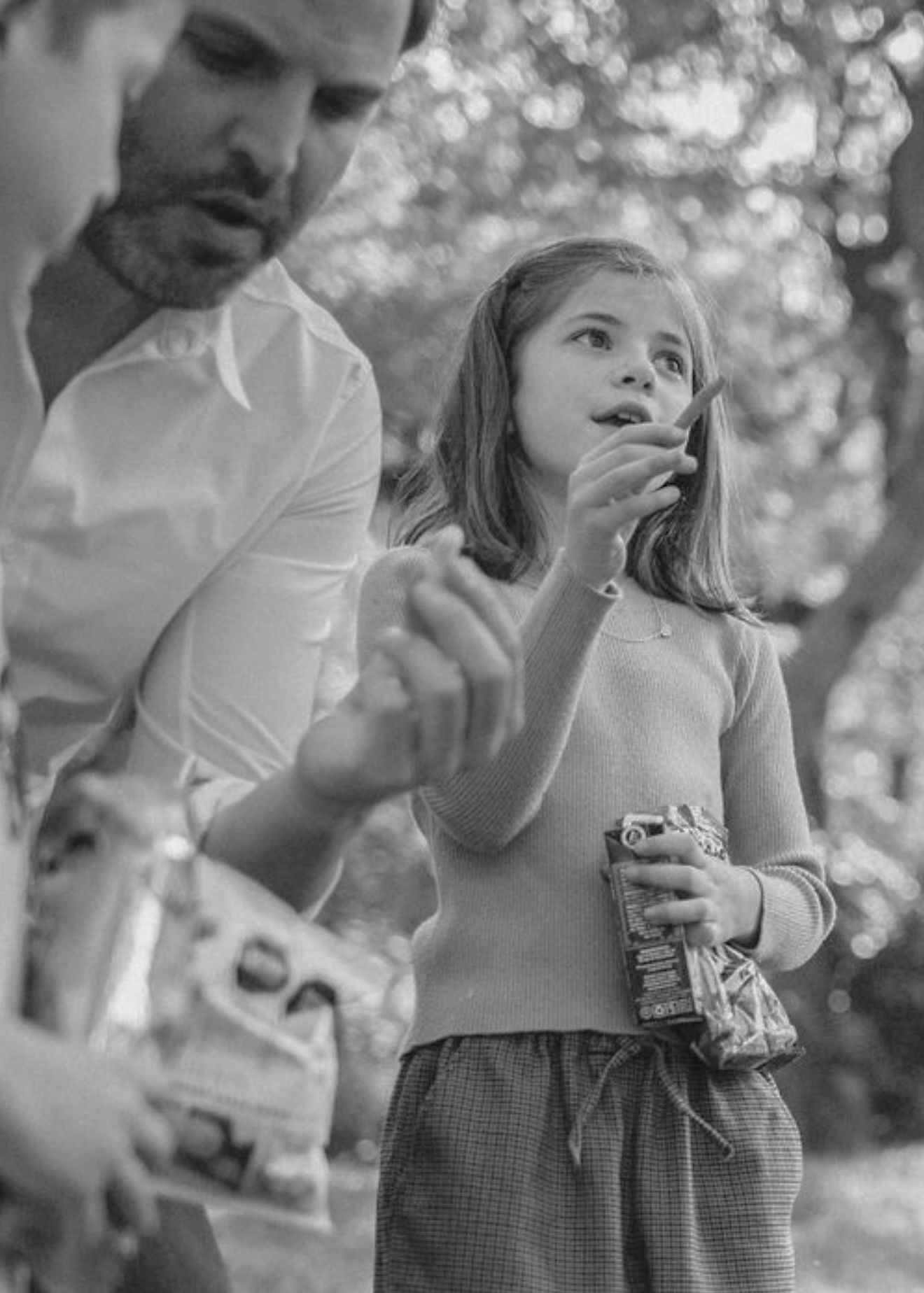 A heartwarming black and white moment outdoors of enjoying ice cream treats together on a sunny afternoon.