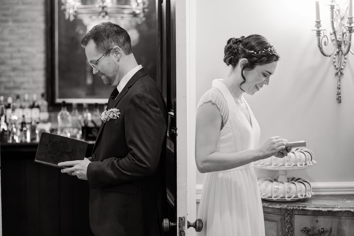 Black and white photo of bride and groom reading private vows separately before their wedding ceremony.