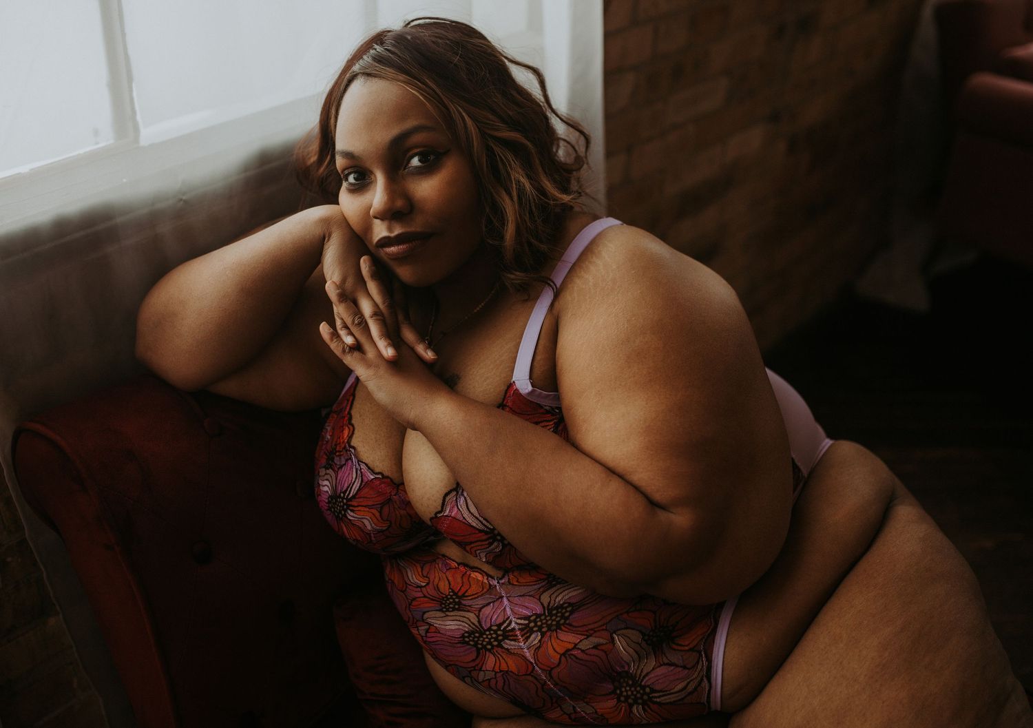 A boudoir photo series showing intimate poses in moody lighting with red lingerie details.
