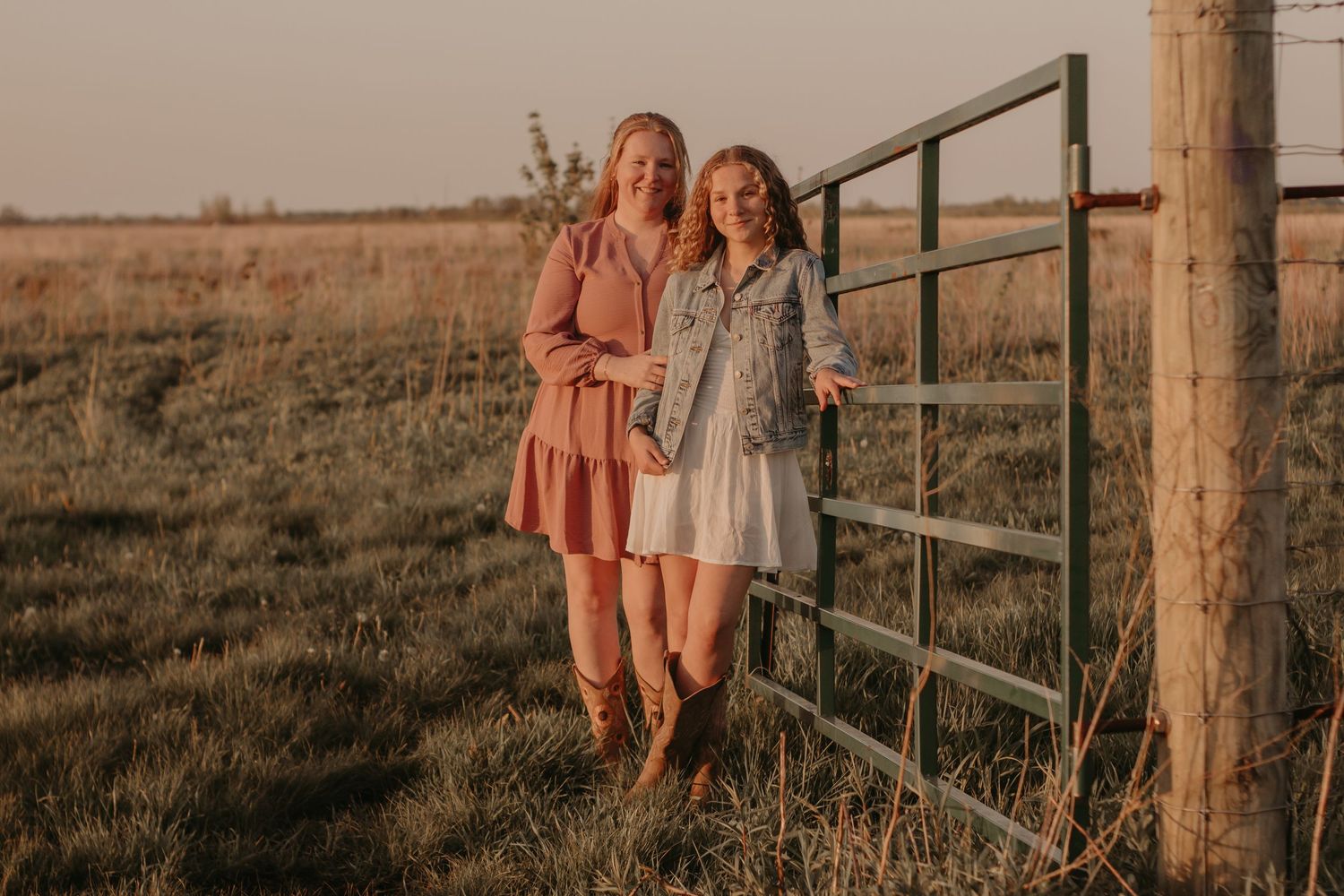 Mother and daughter leaning against a fence in a bison prairie at sunset during an outdoor family photography session in Indiana