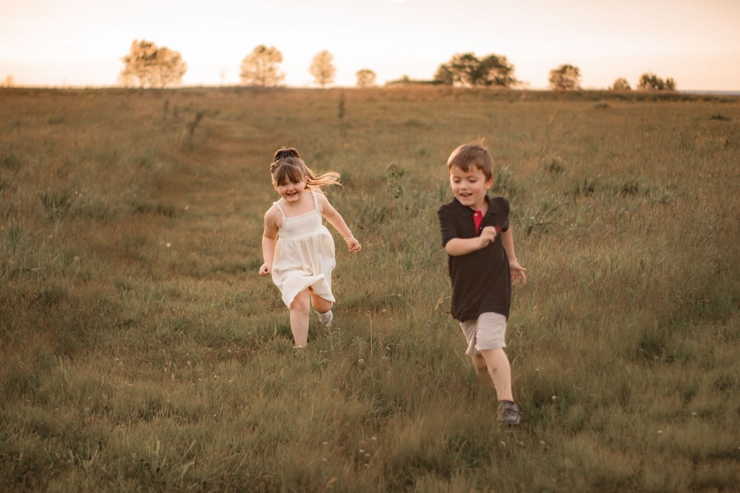 Children running through a prairie landscape in Indiana during an outdoor family photography session