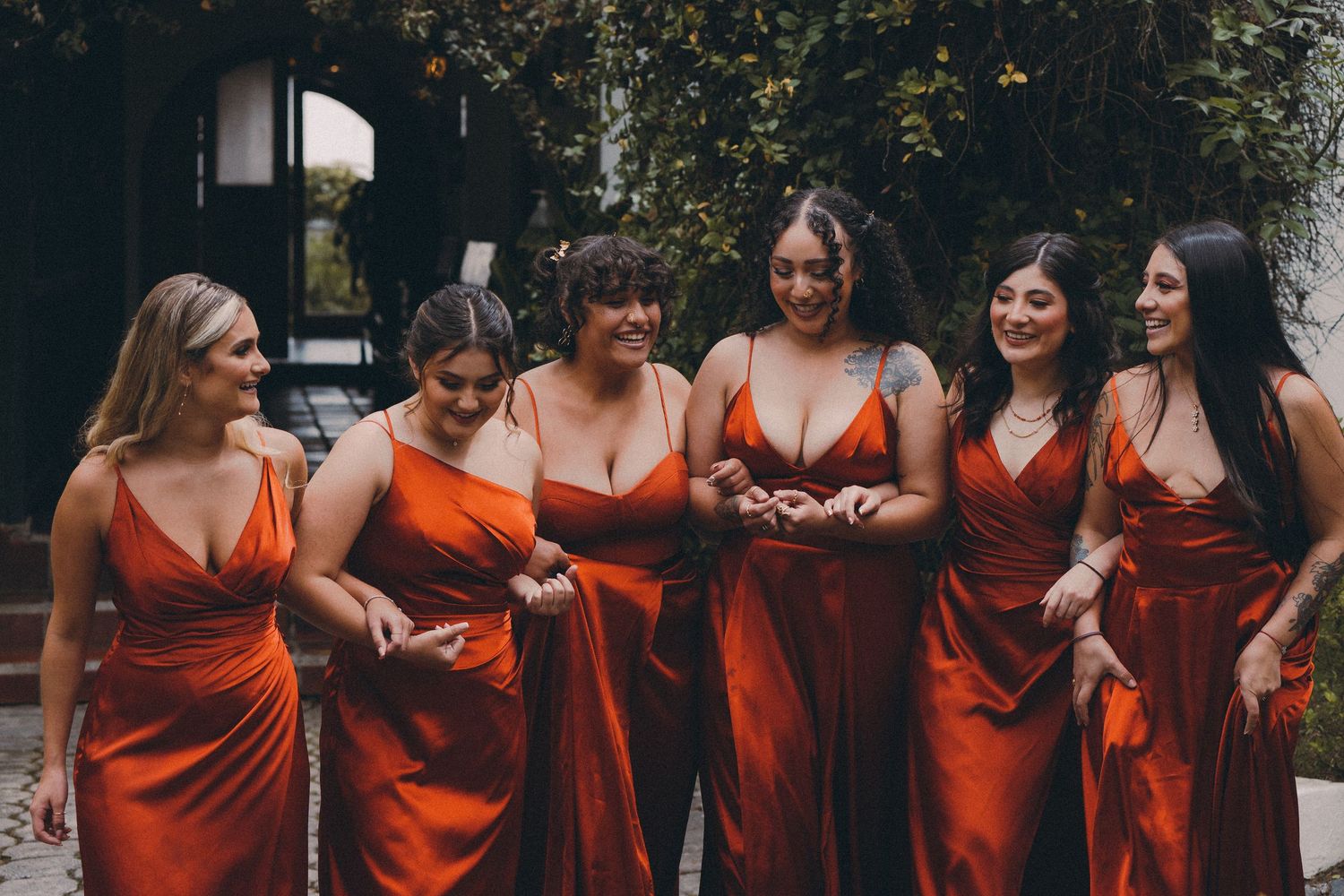 Damas de honor con vestidos rojos, sonriendo felices en tarde de ceremonia de boda campestre. Foto por Nath Rivas. Tomada en Quito Ecuador.