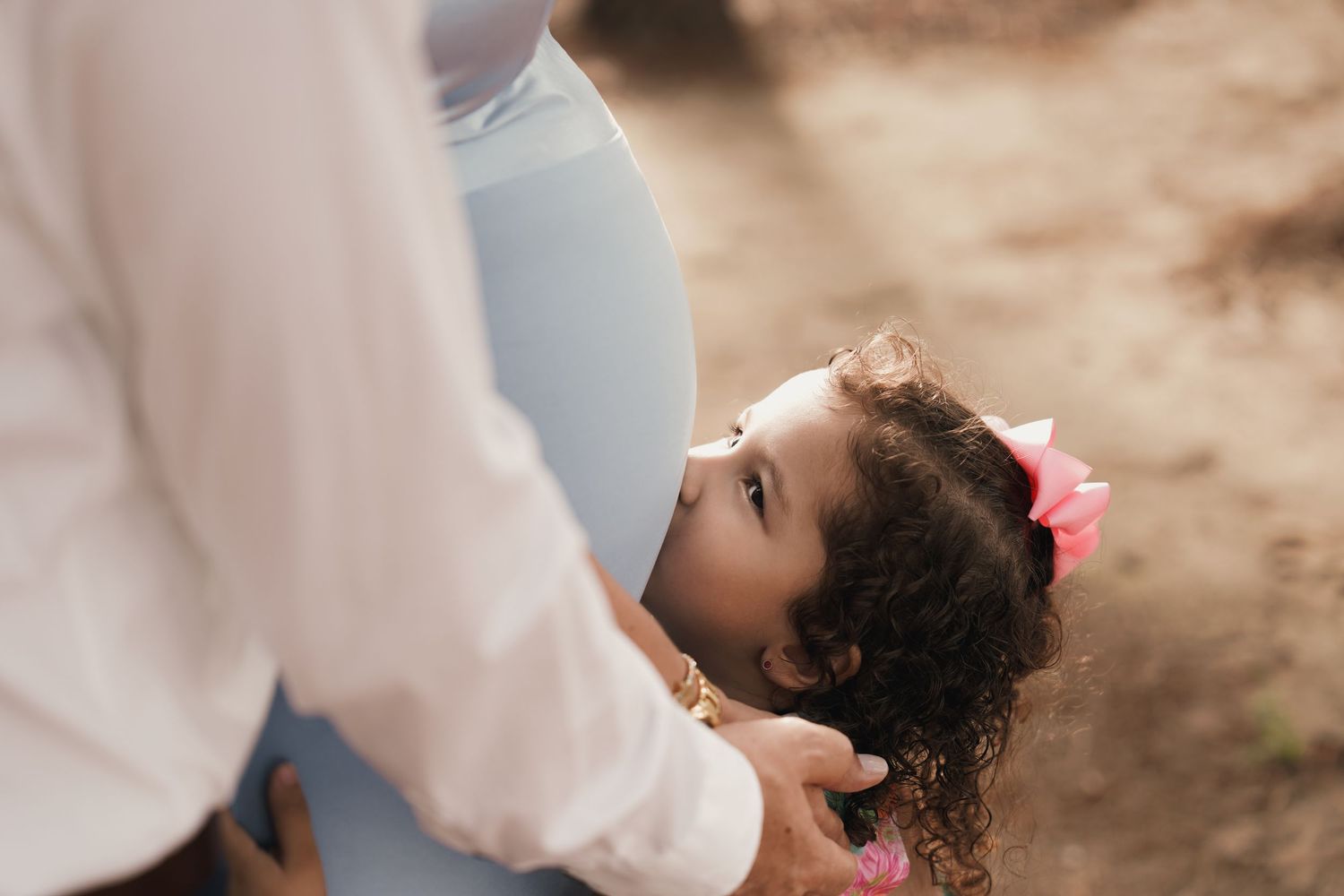 Niña besando el embarazo de su madre en sesión fotográfica campestre. Foto por Nath Rivas.