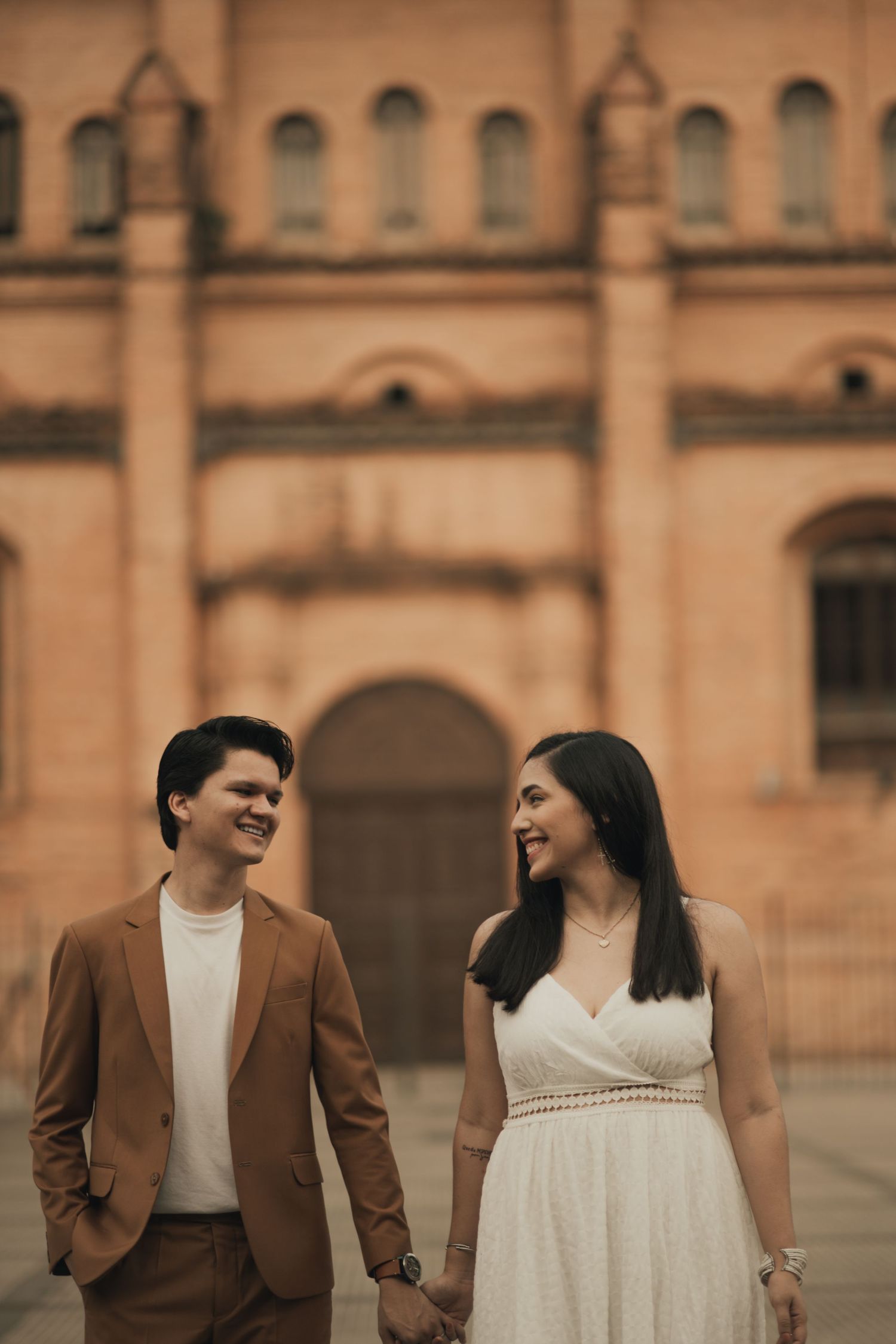 Pareja sonriendo en Plaza Pública, tomados de la mano. Tonos vintage. Editado por Nath Rivas.