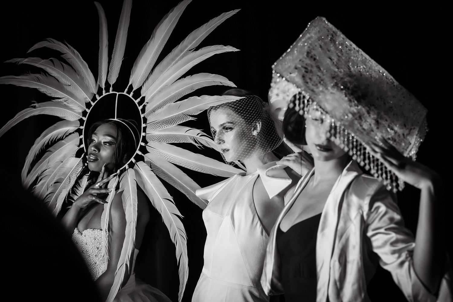 Black and white artistic photograph showing dramatic feathered headdress and ceremonial costume in theatrical lighting.