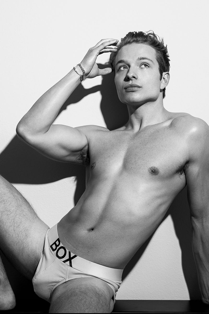 Black and white photo of a male model in underwear against a white background.