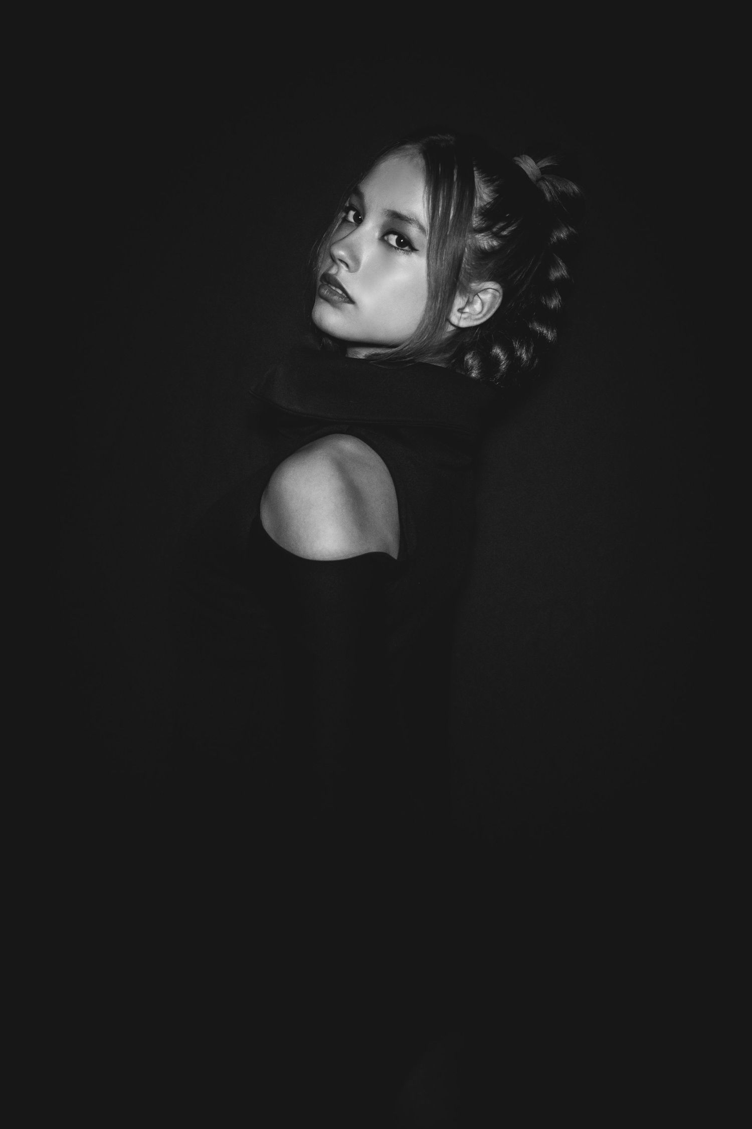 Dramatic black and white portrait with moody lighting captures a side profile against dark background.