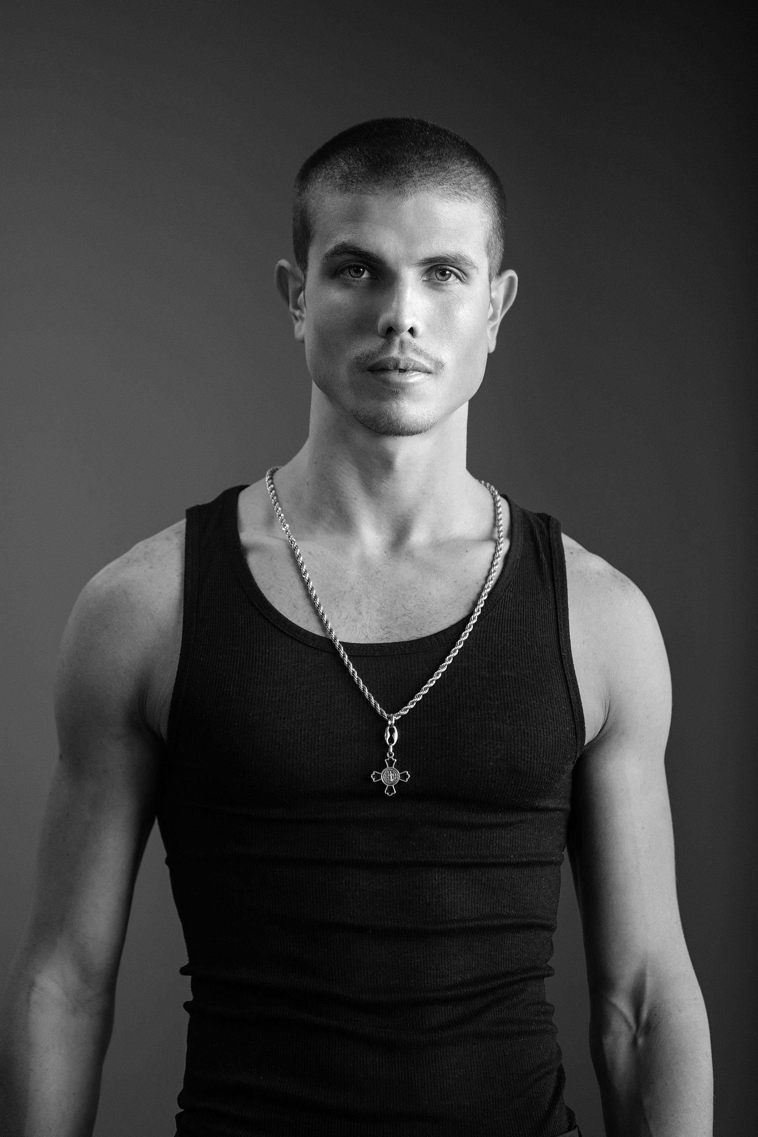 Black and white portrait series showing a person in a black tank top with a necklace against a dark background.
