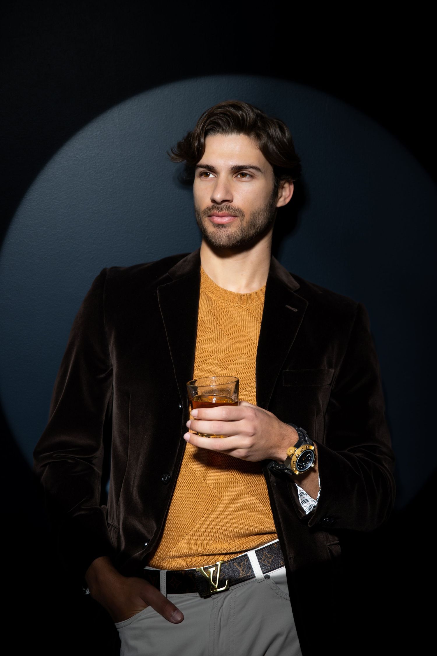 A series of portrait photos showing someone wearing a brown turtleneck and dark velvet jacket against a black background.