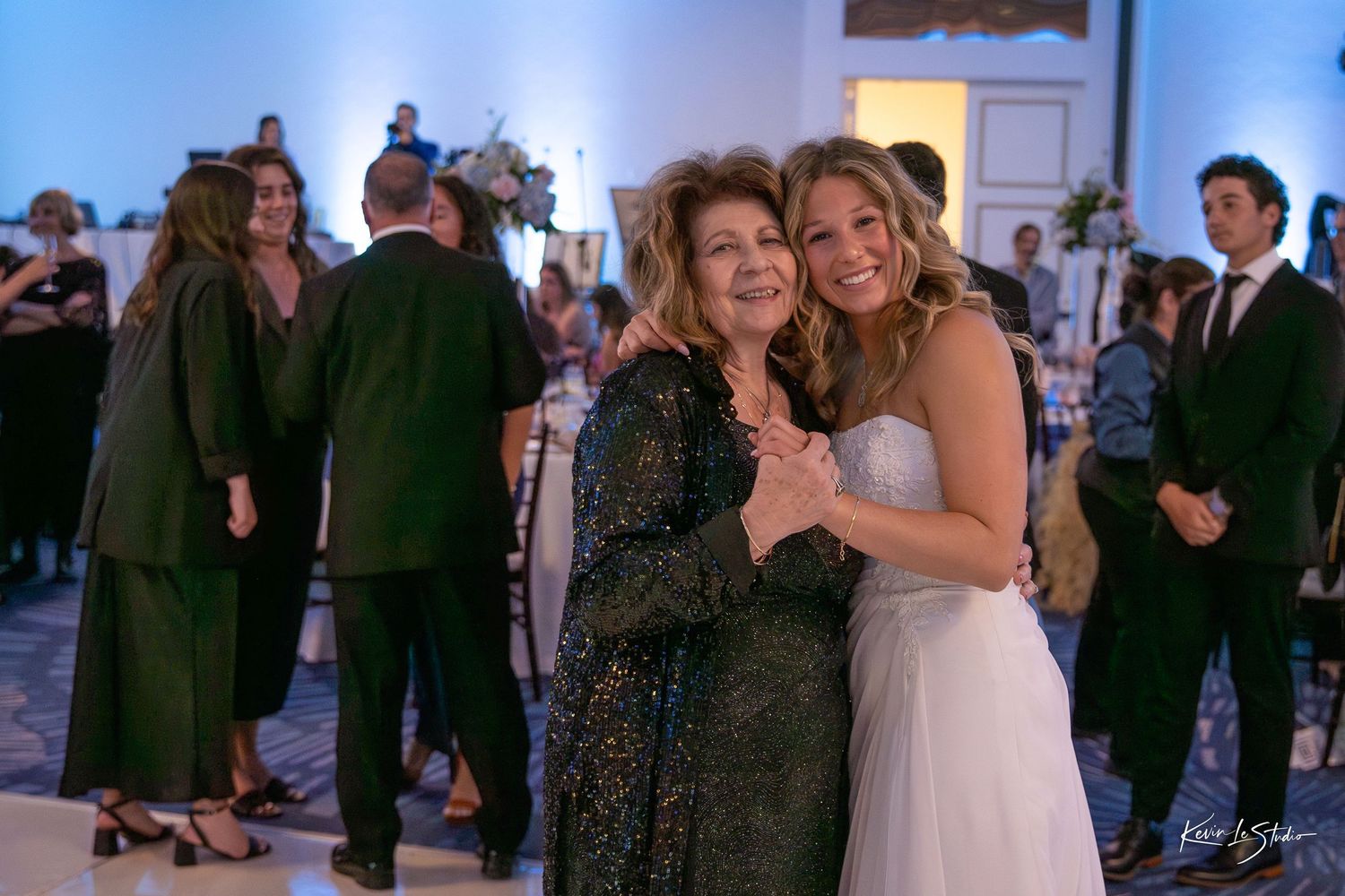 Wedding guests dancing and celebrating together on the dance floor at an indoor reception venue.