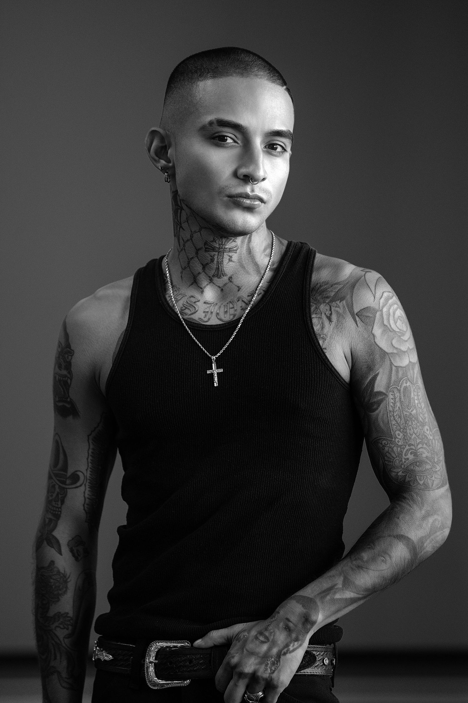 Black and white portraits showcase a person in a black tank top with visible tattoos and cross necklace in dramatic lighting.