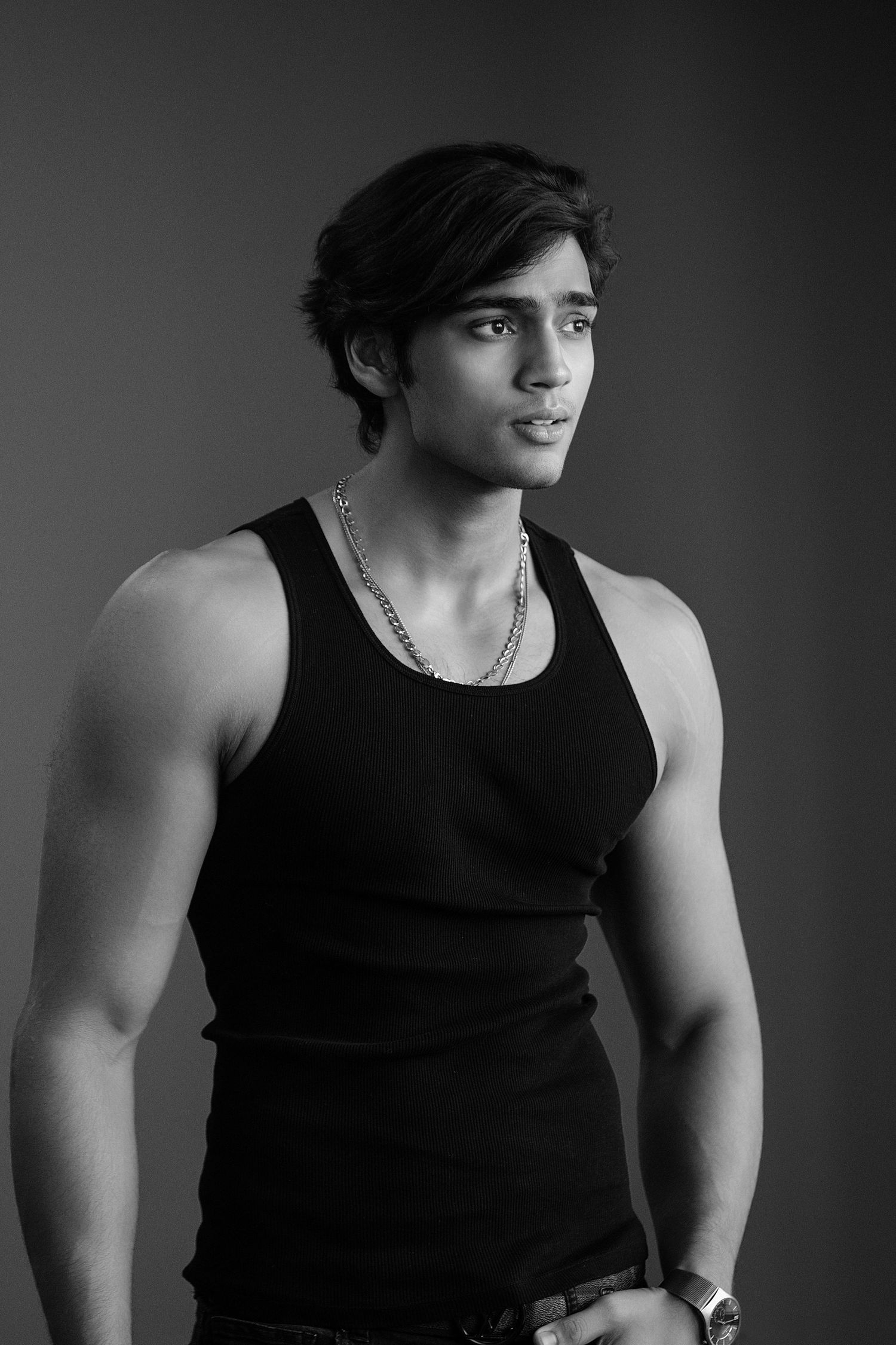 Black and white portrait series showing a muscular person in a sleeveless top against a dark background.