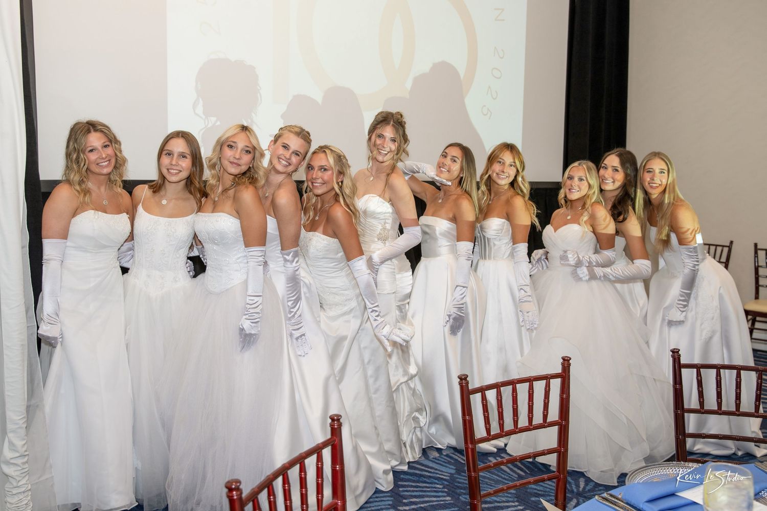 A group wearing white robes poses together in what appears to be a bridal party or spa setting.
