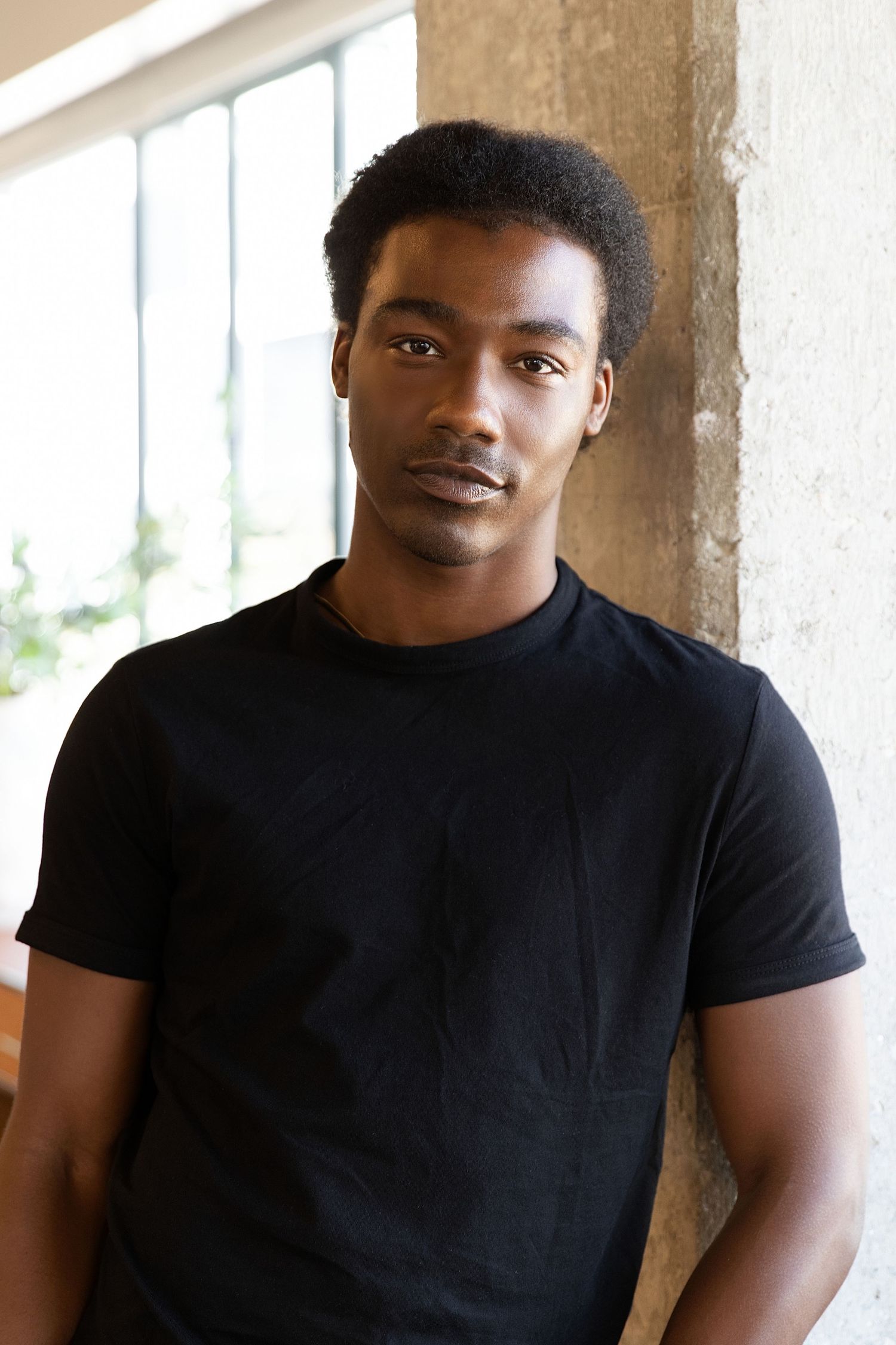 Four similar portrait photos of someone wearing a black t-shirt against a light colored background.