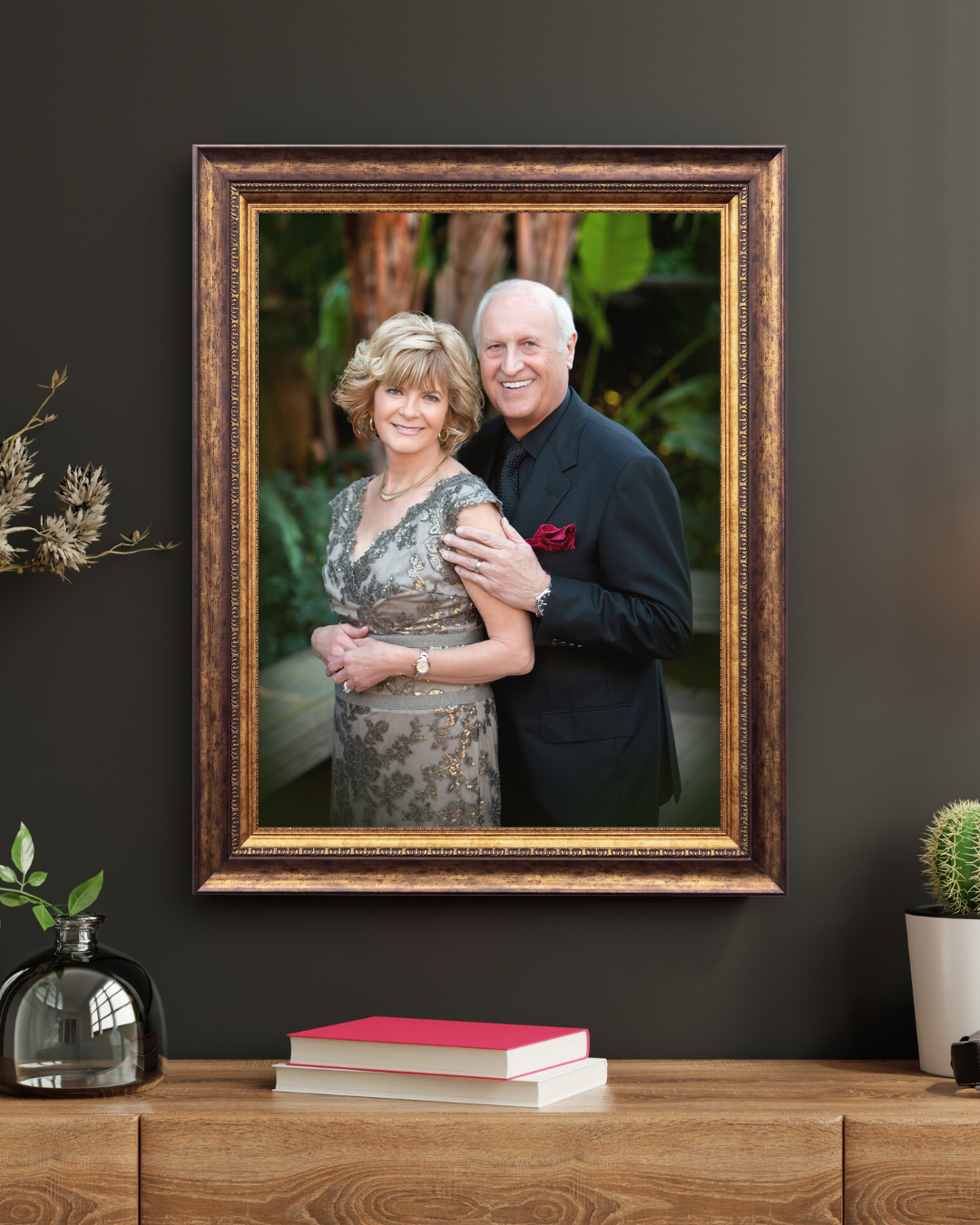 Collection of framed portraits displayed on dark wall with wooden console table.
