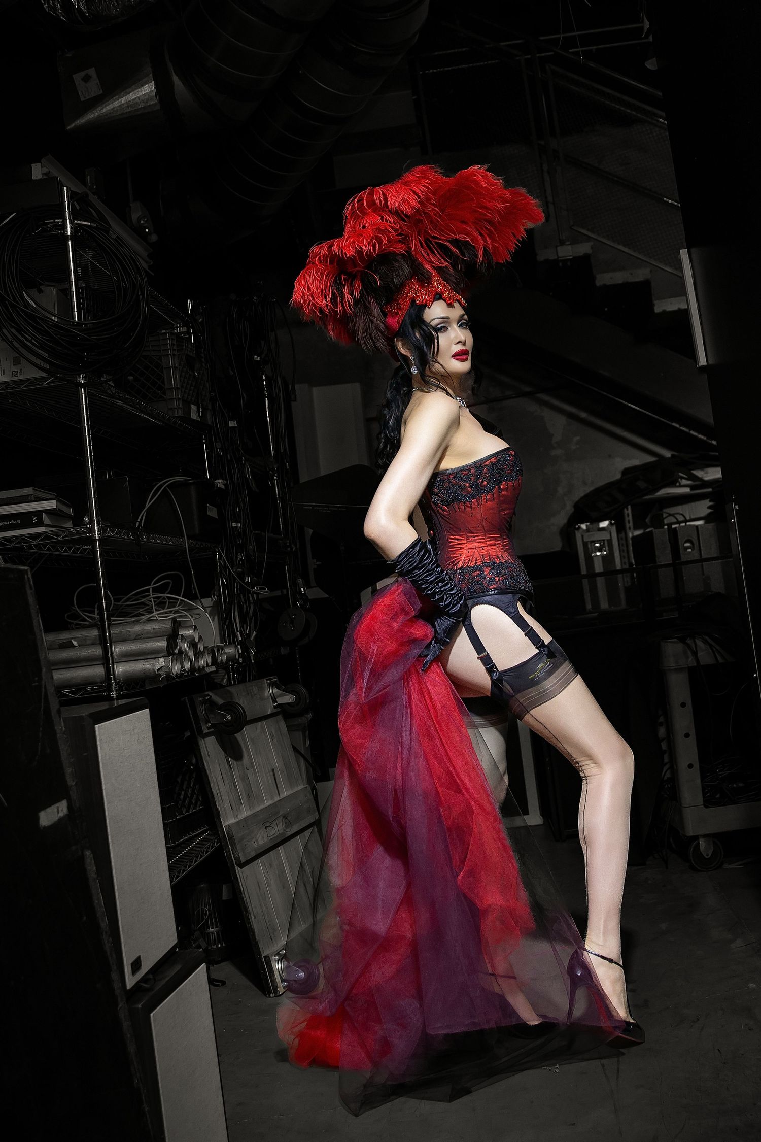 A dramatic fashion photo series showing a red and black tulle dress being modeled in a dark industrial setting.